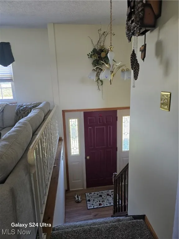 Foyer with a textured ceiling, wood finished floors, and a chandelier