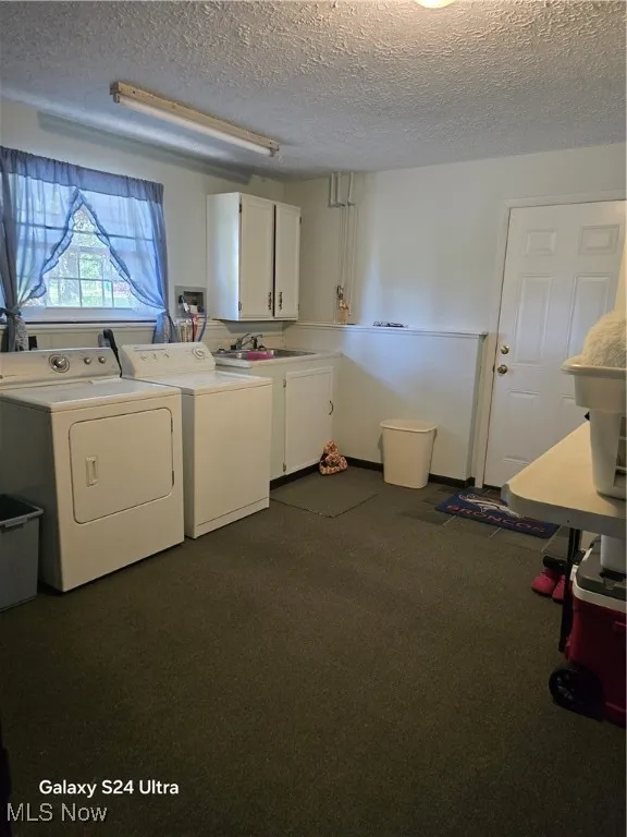 Laundry room featuring a textured ceiling, independent washer and dryer, cabinet space, and dark colored carpet