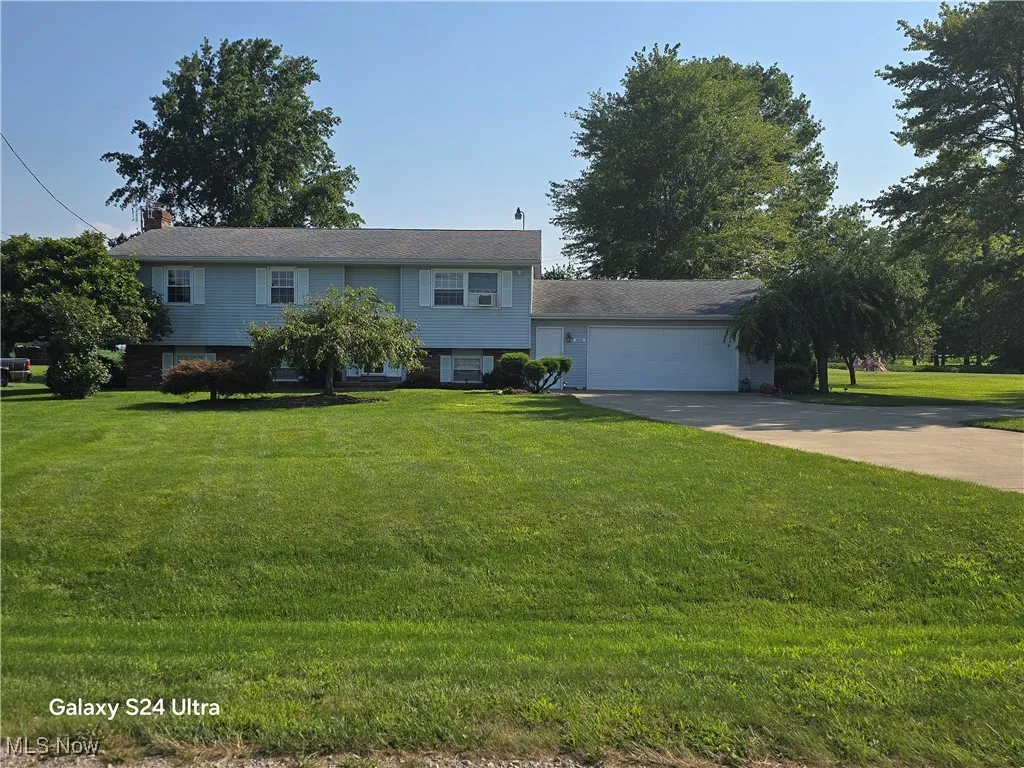 View of front of house featuring a front yard, a garage, and driveway