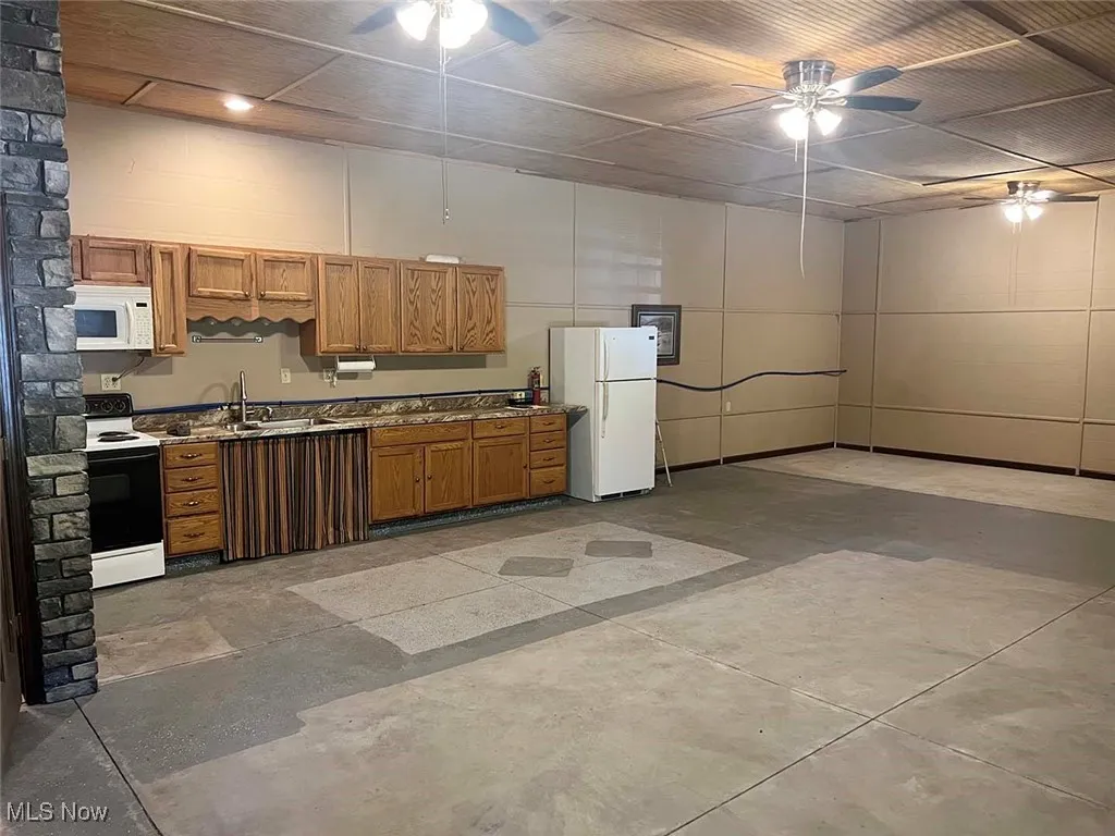 Kitchen with ceiling fan, white appliances, and brown cabinets