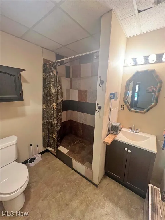 Bathroom featuring a stall shower, vanity, and a drop ceiling