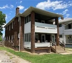 Back of house with a balcony, a chimney, crawl space, and a lawn