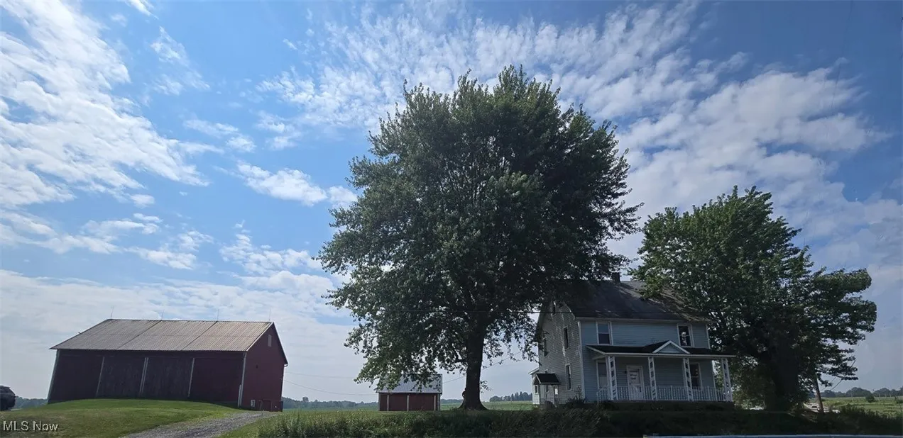 View of side of property with an outbuilding and a porch