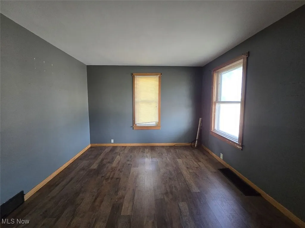 Spare room featuring baseboards and dark wood finished floors