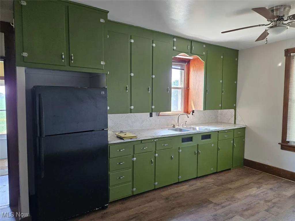 Kitchen featuring light countertops, freestanding refrigerator, dark wood-style floors, and a ceiling fan