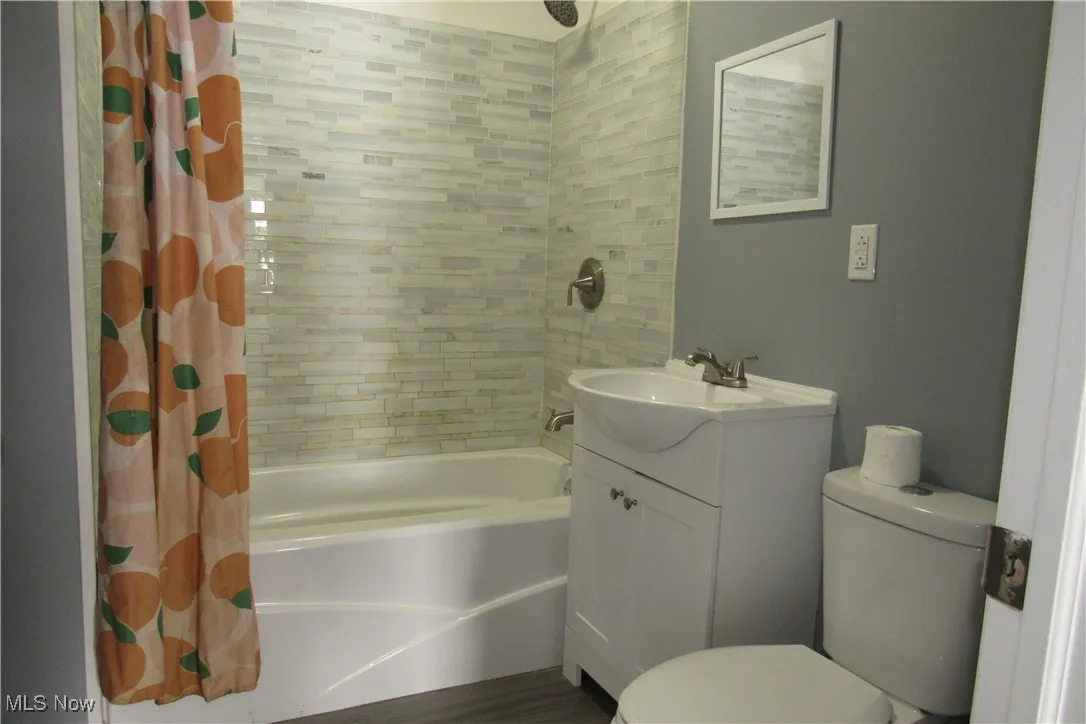Full bath featuring shower / tub combo, vanity, and vinyl flooring