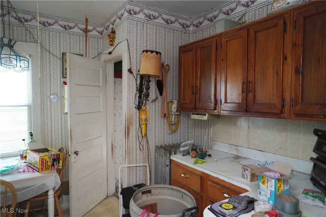 Kitchen featuring brown cabinets, light countertops, and wallpapered walls