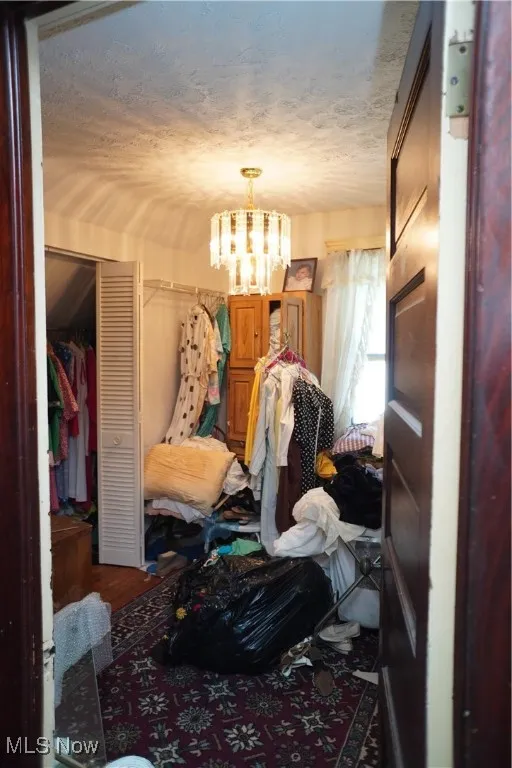 Bedroom with a chandelier, a textured ceiling, and a closet