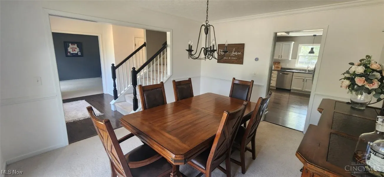 Dining area with a chandelier, stairs, ornamental molding, and light wood-style floors