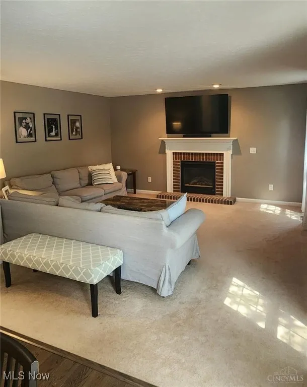 Living room with a brick fireplace, carpet floors, and recessed lighting