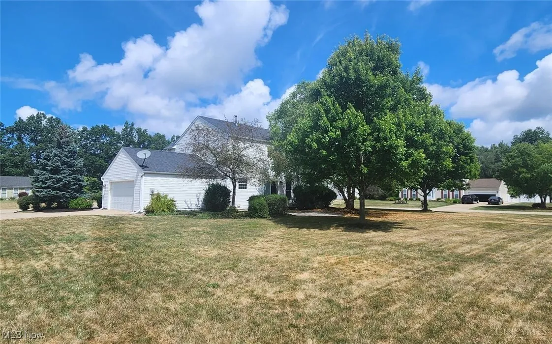 View of front of property featuring driveway, a front yard, and an attached garage