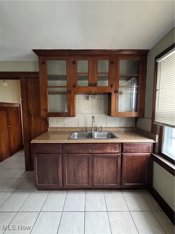 Kitchen featuring light tile patterned flooring, decorative backsplash, and light countertops