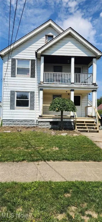 View of front of property with covered porch and a front lawn