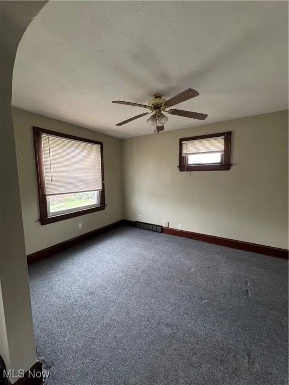 Carpeted spare room with baseboards and a ceiling fan