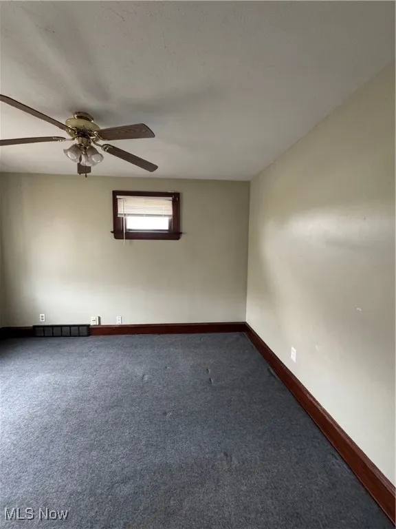 Carpeted spare room featuring ceiling fan and a textured ceiling