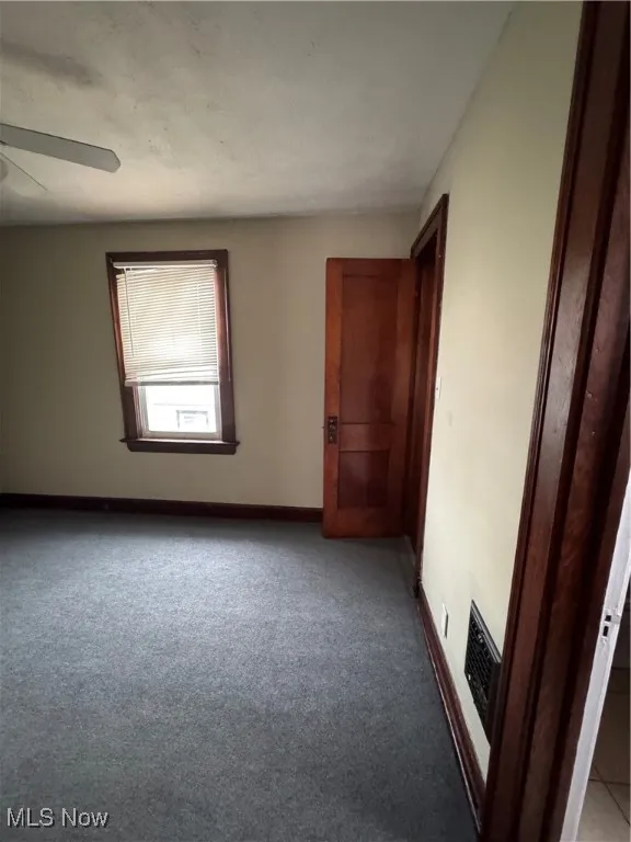 Unfurnished bedroom featuring ceiling fan and carpet floors