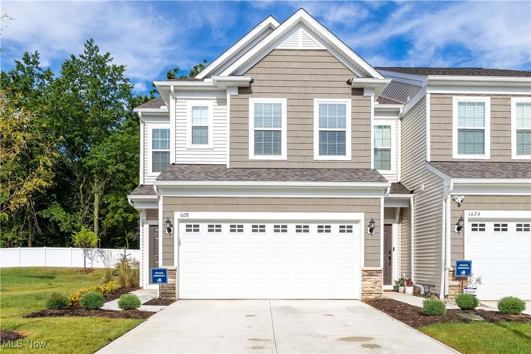 Craftsman-style home featuring driveway, an attached garage, stone siding, and a shingled roof