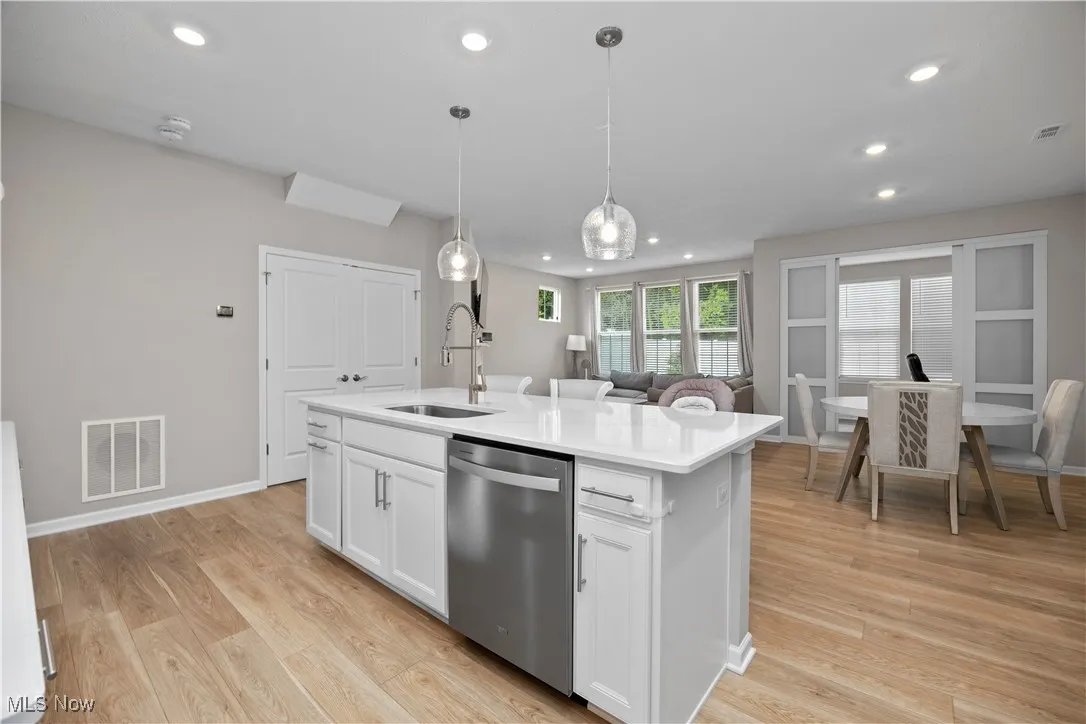Kitchen featuring dishwasher, white cabinets, recessed lighting, light wood finished floors, and hanging light fixtures