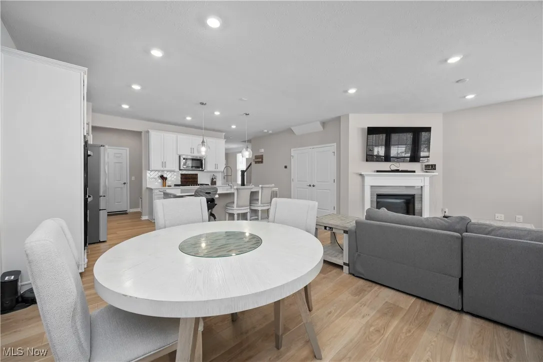 Dining area featuring recessed lighting, light wood-type flooring, and a glass covered​​‌​​​​‌​​‌‌​‌‌​​​‌‌​‌​‌​‌​​​‌​​ fireplace