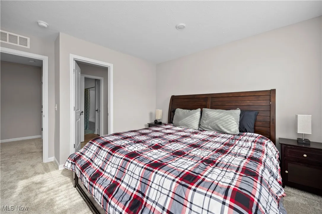 Bedroom featuring light colored carpet and connected bathroom