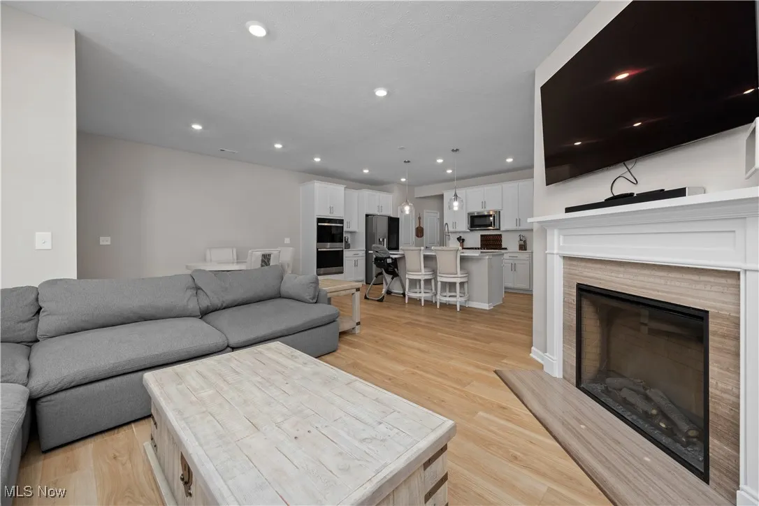 Living room featuring a glass covered fireplace, recessed lighting, and light wood finished floors