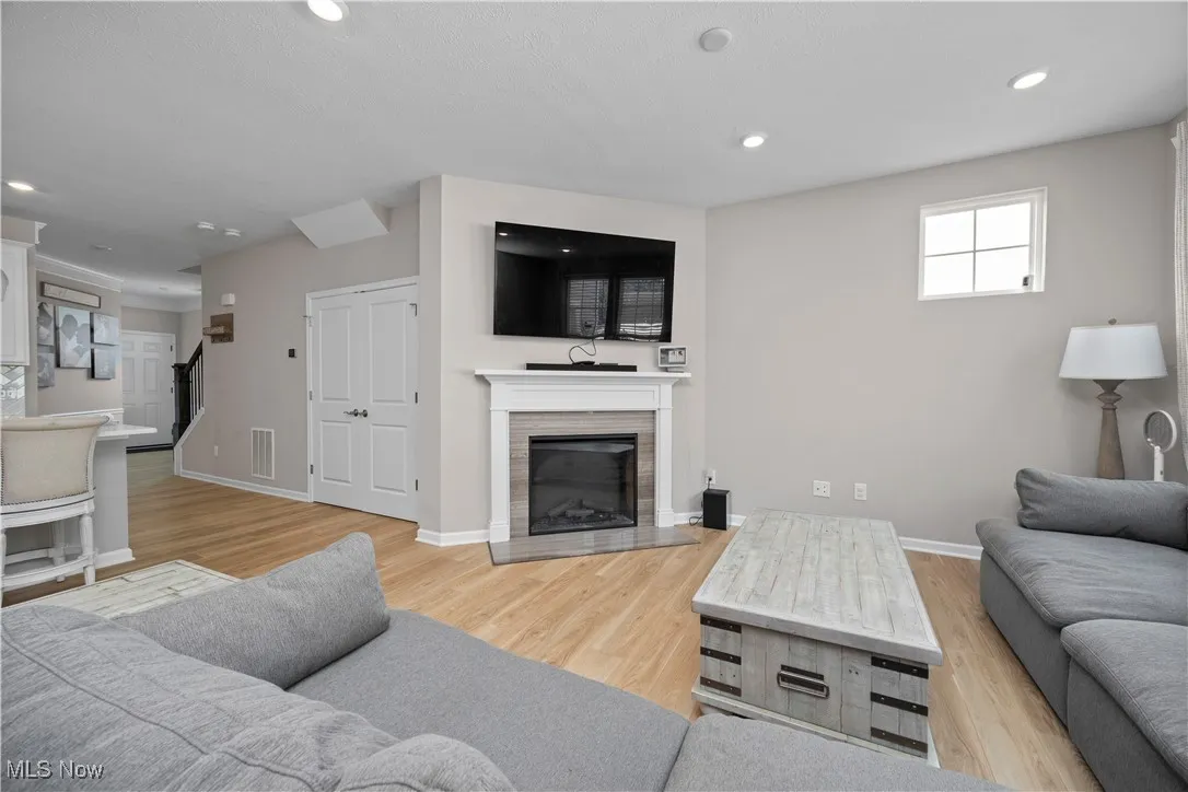 Living room with light wood-style flooring, a fireplace, and recessed lighting