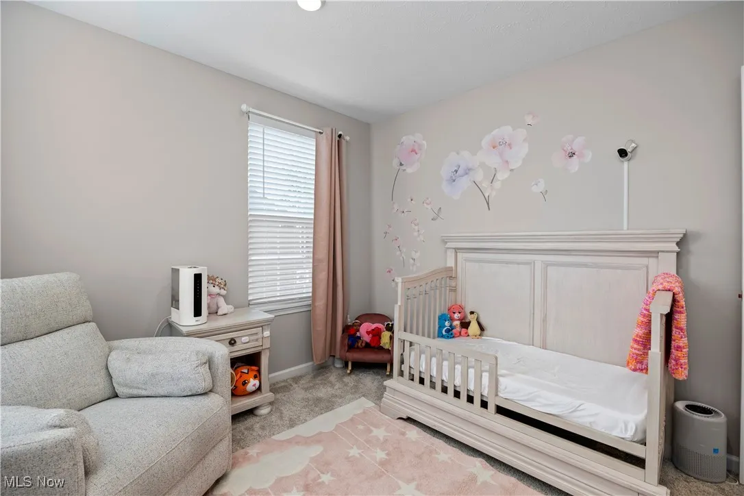 Carpeted bedroom with a nursery area and baseboards