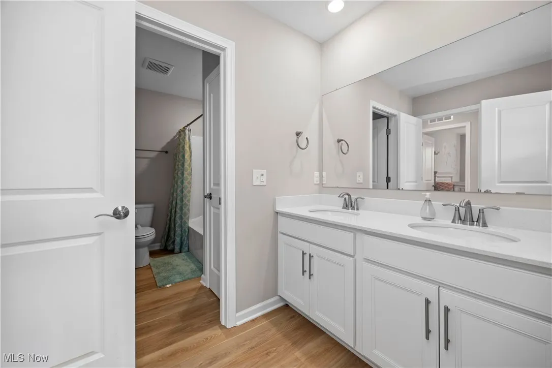 Full bathroom featuring light wood finished floors, double vanity, and shower / tub combo