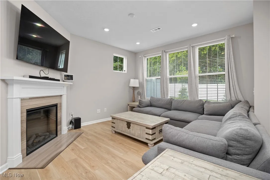 Living room featuring a glass covered fireplace, light wood-type flooring, plenty of natural light, and recessed lighting