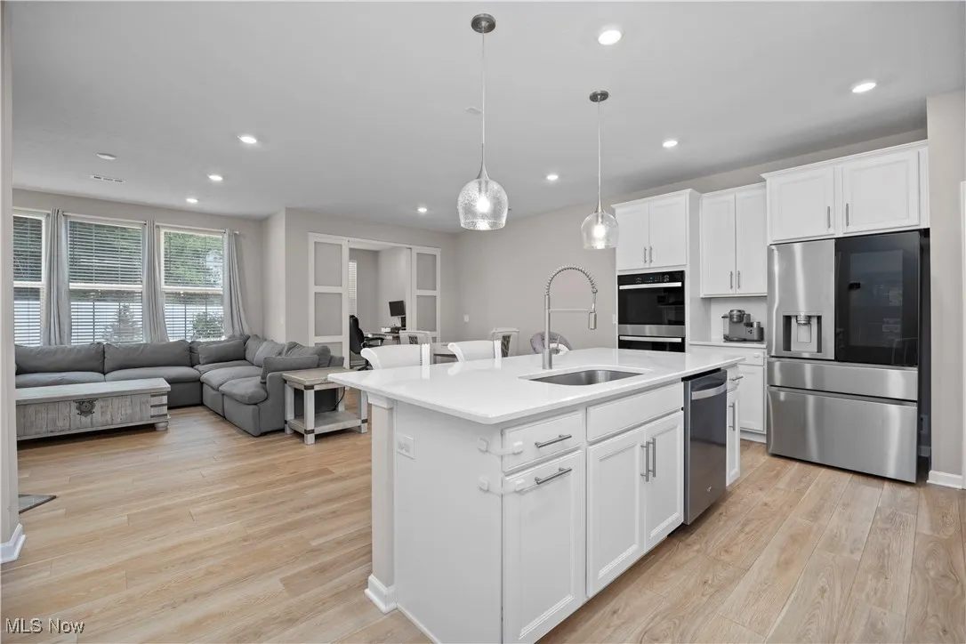 Kitchen featuring stainless steel appliances, white cabinets, recessed lighting, light wood finished floors, and pendant lighting