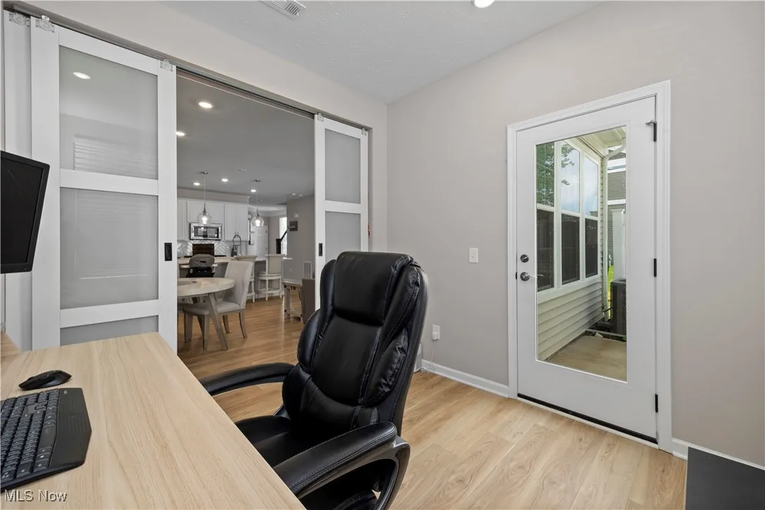 Home office featuring light wood-style flooring, recessed lighting, and a barn door