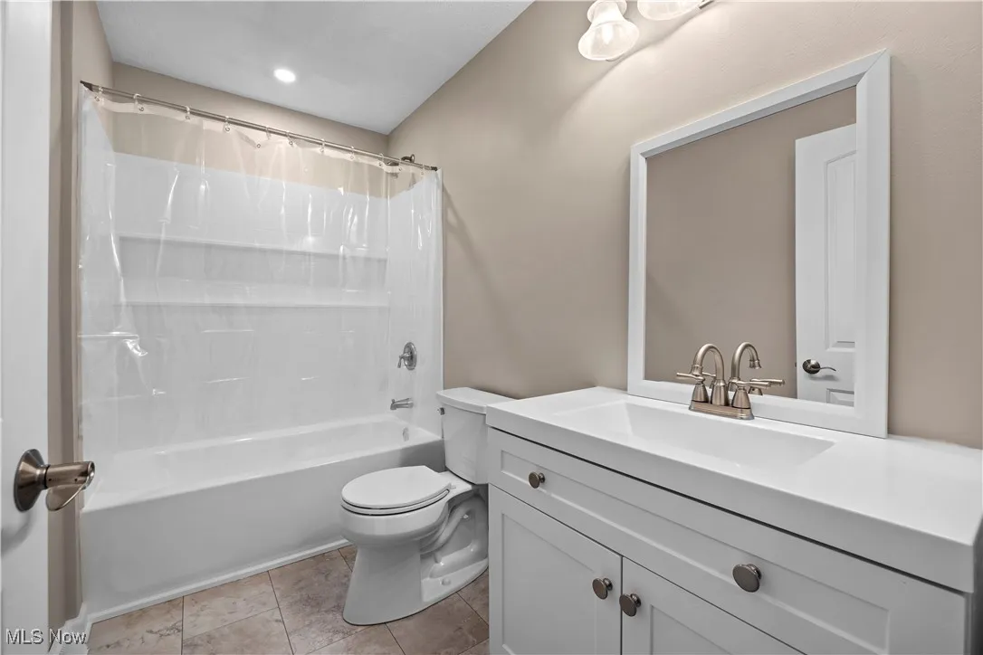 Bathroom featuring shower / tub combo with curtain, vanity, and light tile patterned floors