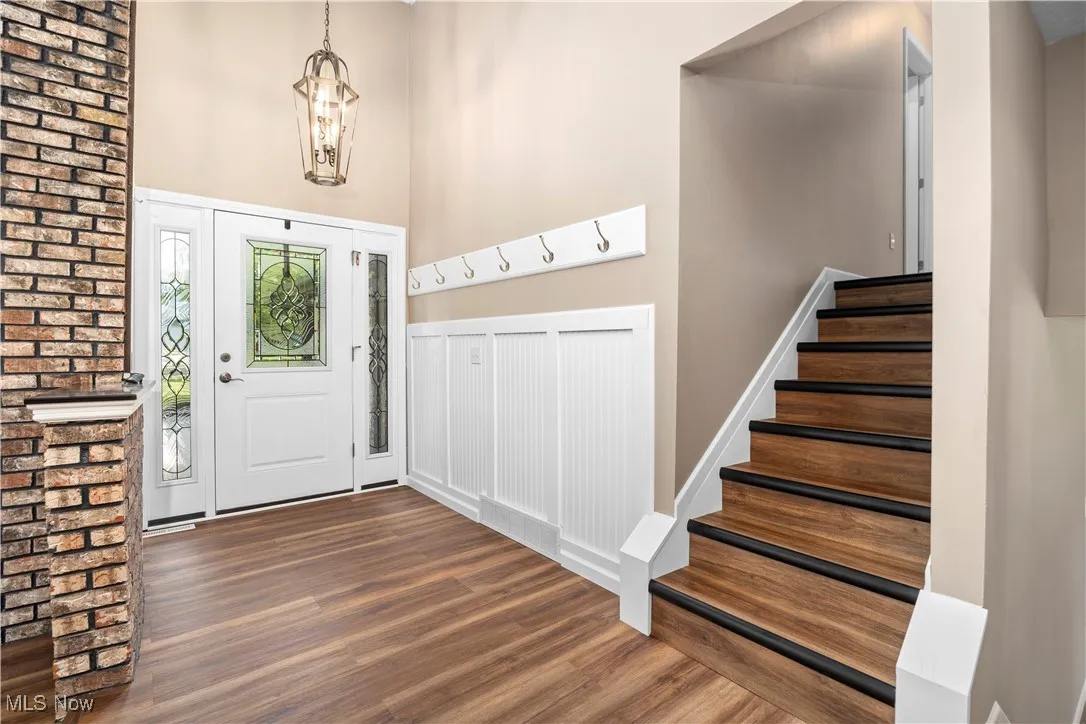 Foyer featuring wood finished floors, stairs, and a chandelier