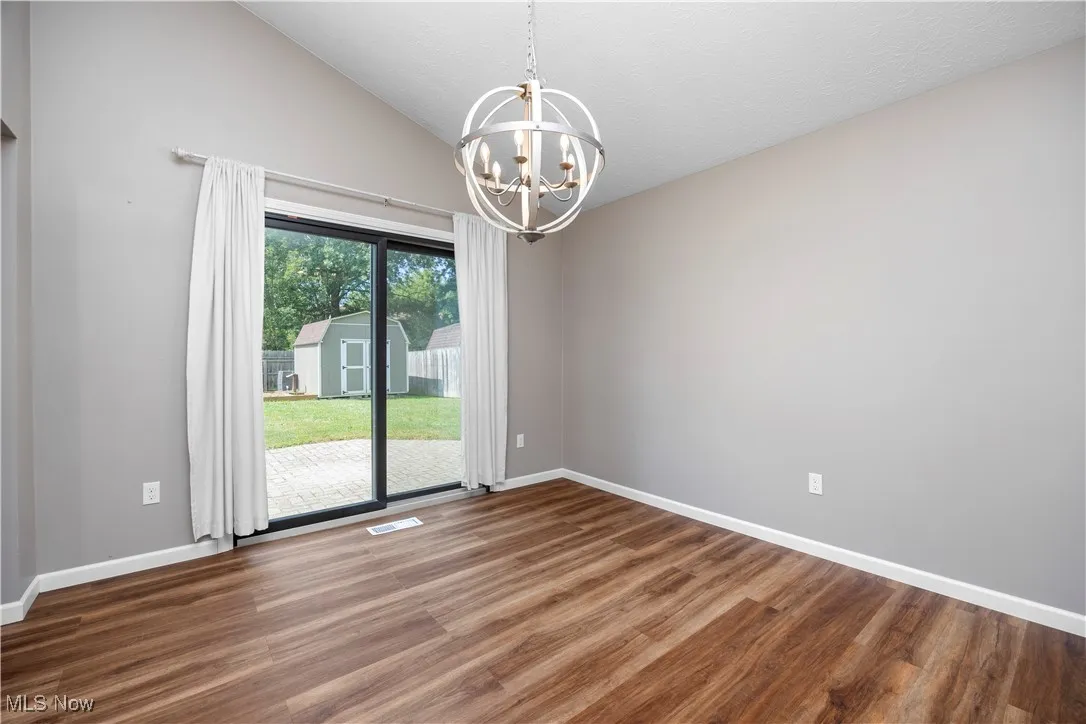 Unfurnished dining area with lofted ceiling, wood finished floors, and a chandelier