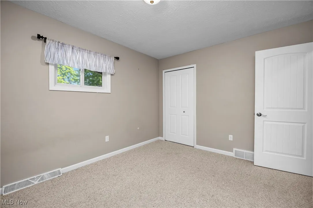 Unfurnished bedroom featuring a textured ceiling, carpet, and a closet