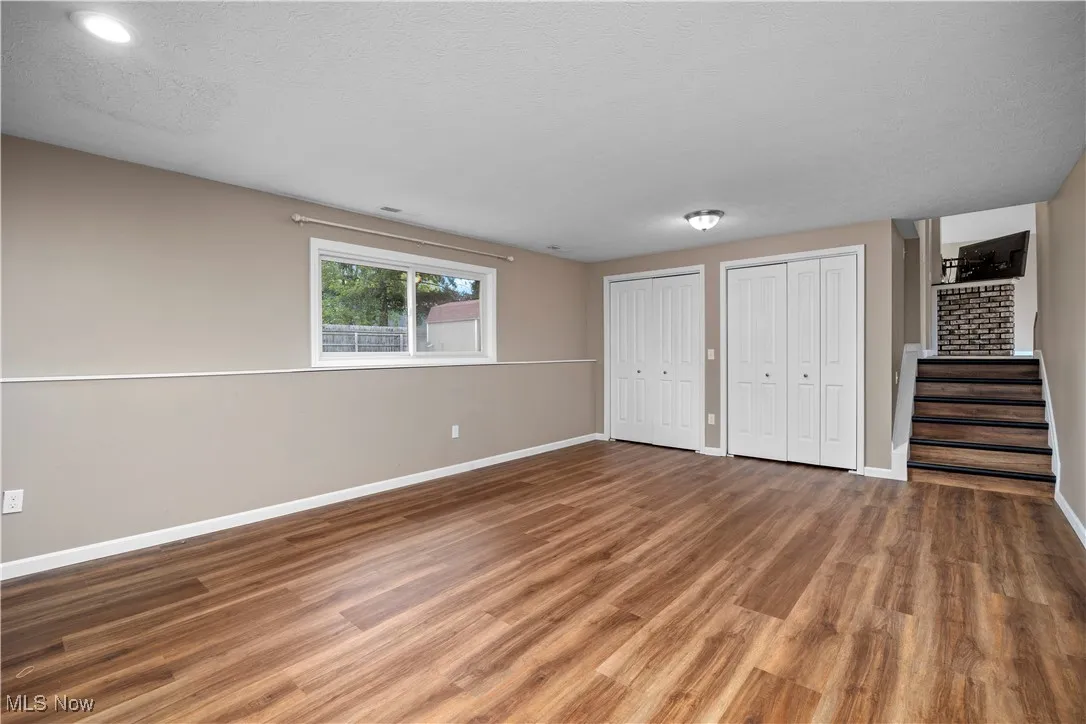 Unfurnished bedroom featuring wood finished floors, multiple closets, and a textured ceiling