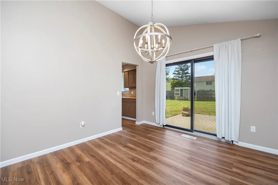 Unfurnished dining area with lofted ceiling, dark wood-style flooring, and a chandelier