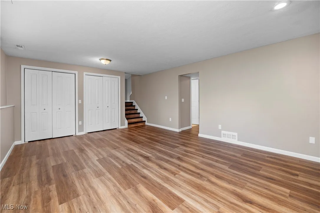 Unfurnished living room featuring stairs and wood finished floors