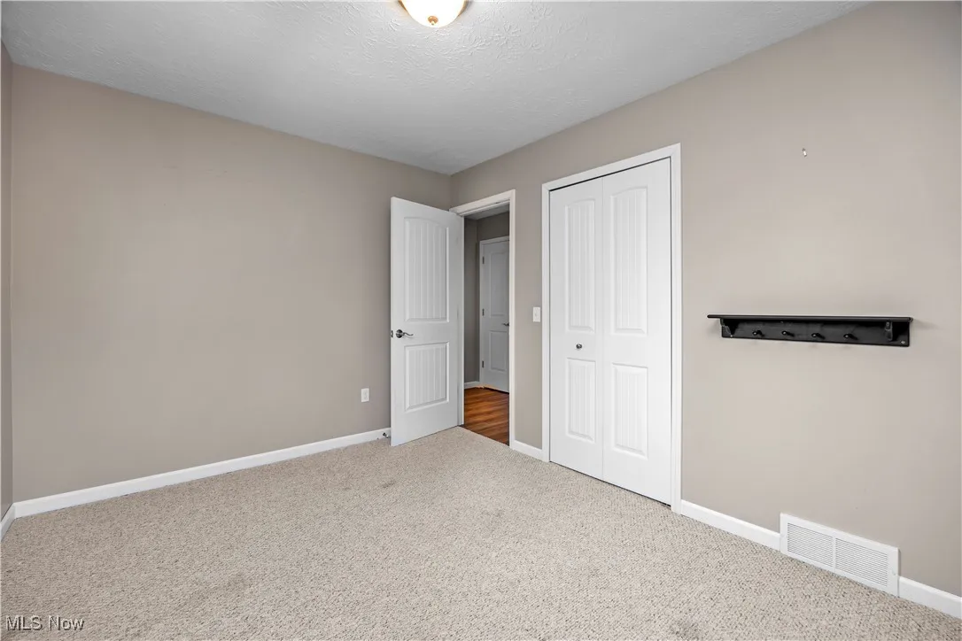 Unfurnished bedroom featuring carpet, a closet, and a textured ceiling