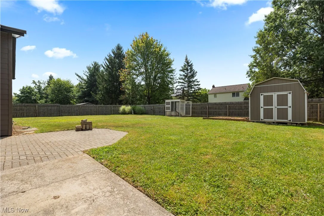 Fenced backyard featuring a storage unit and a patio area