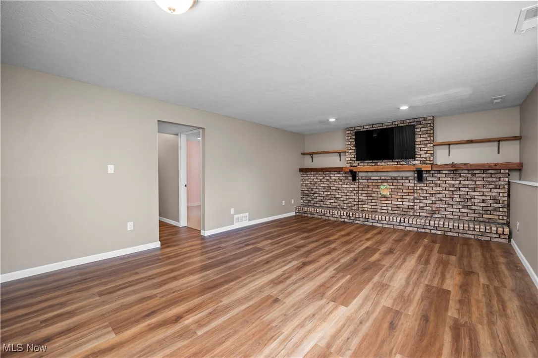 Unfurnished living room with wood finished floors, a textured ceiling, and recessed lighting