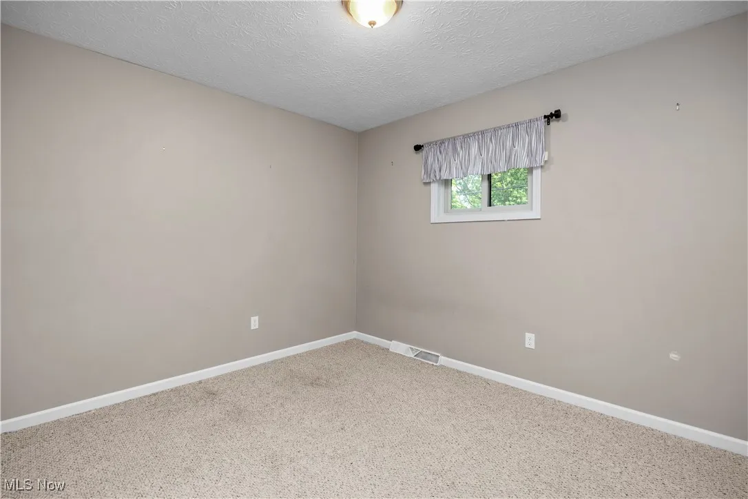 Empty room with carpet flooring and a textured ceiling