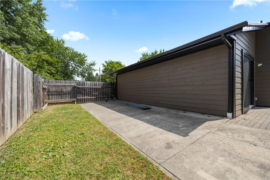 View of side of home featuring a fenced backyard and a gate