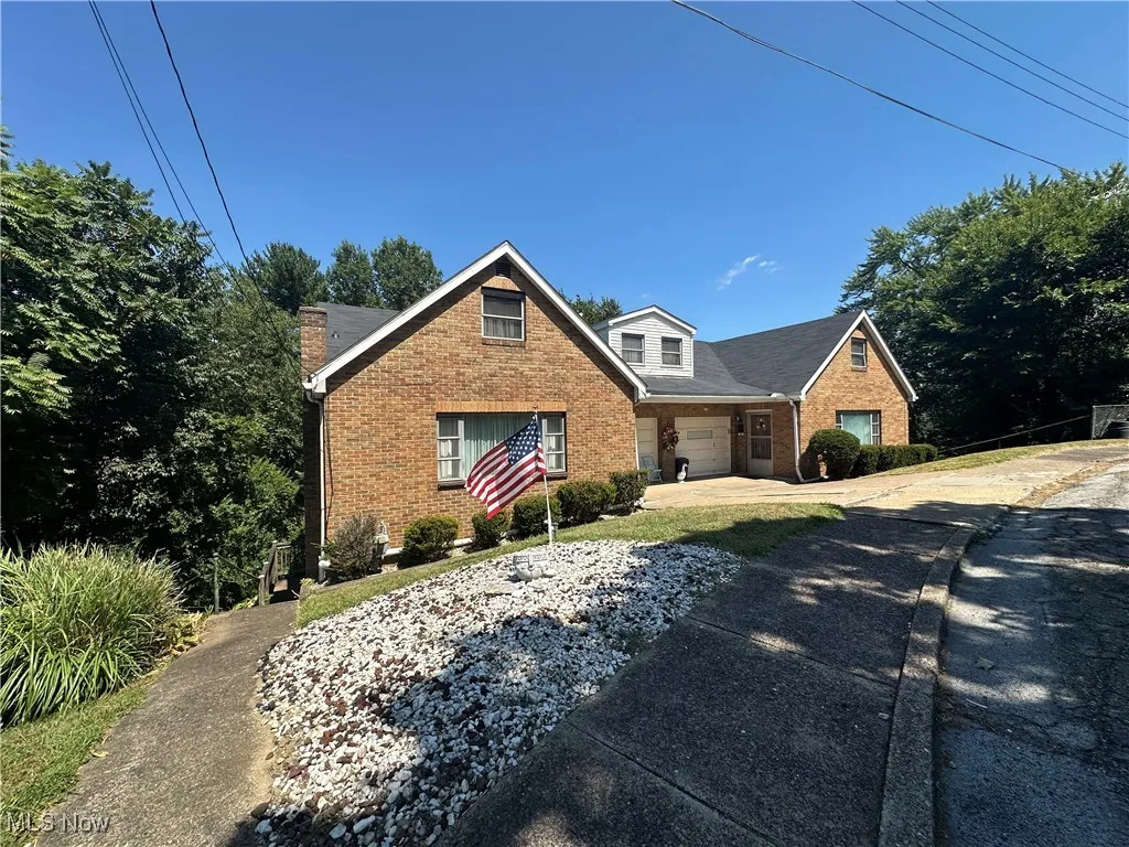 View of front of home with brick siding, a garage, concrete driveway, and covered porch