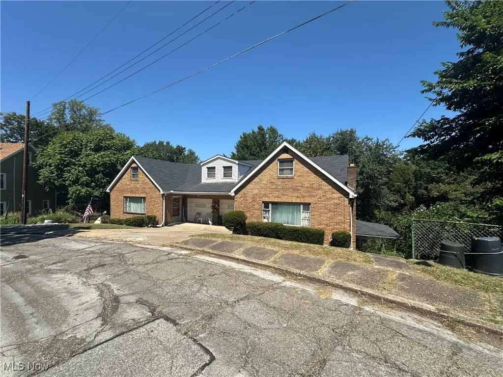 View of front facade with a porch, an attached garage, brick siding, and driveway