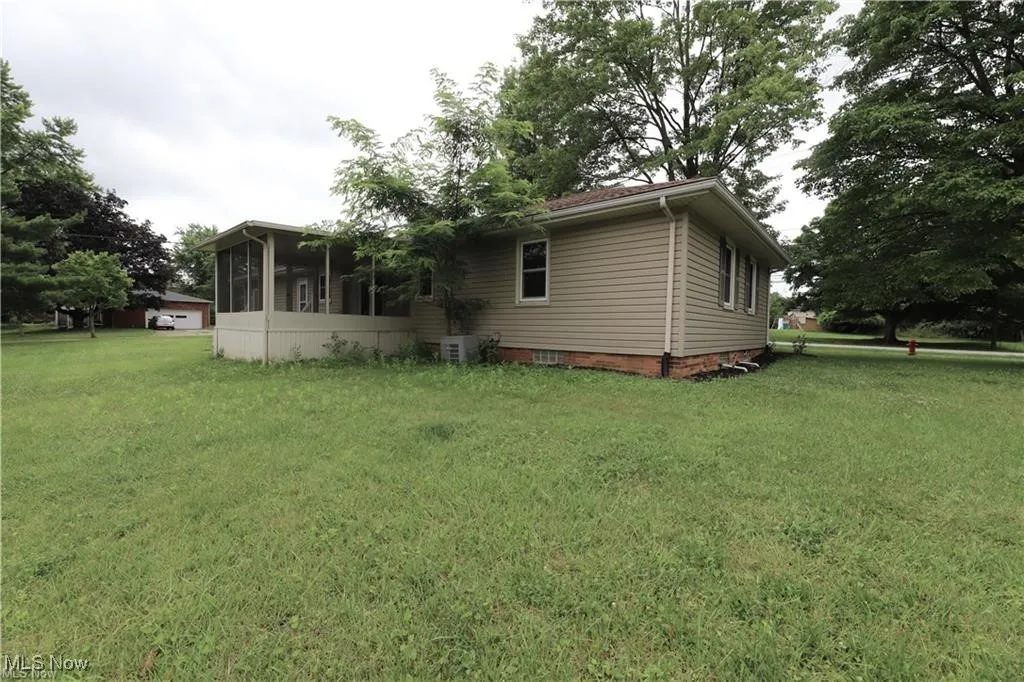 Back of house with a sunroom and a lawn