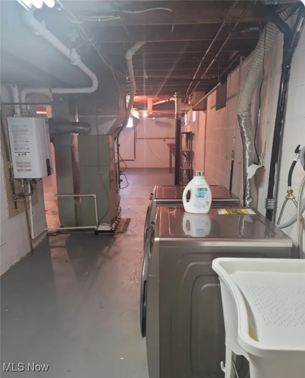 Unfinished basement with tankless water heater and washer and clothes dryer