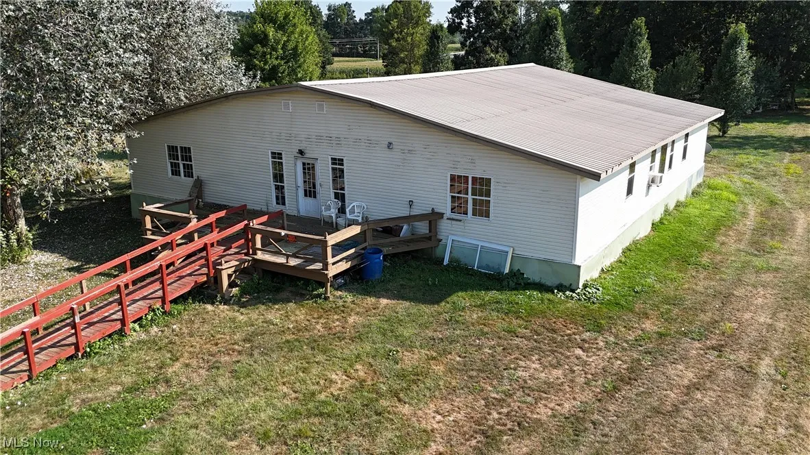 Rear view of house featuring a yard, a metal roof, and a deck