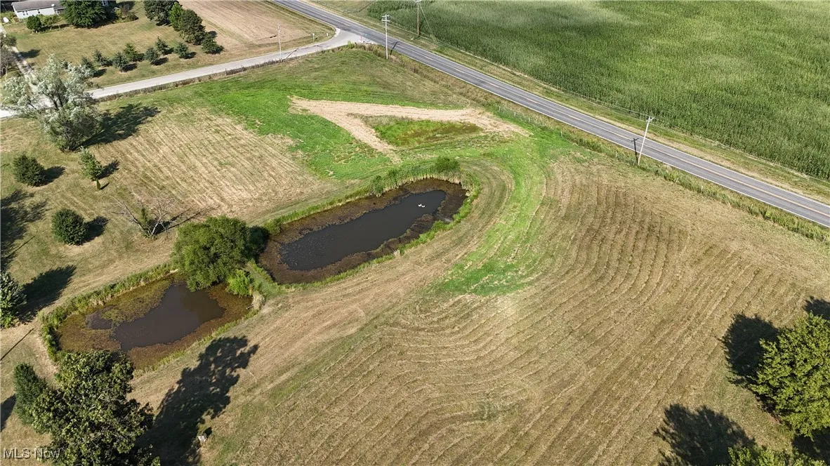 Aerial view of property and surrounding area featuring a large body of water, rural landscape, and abundant farmland