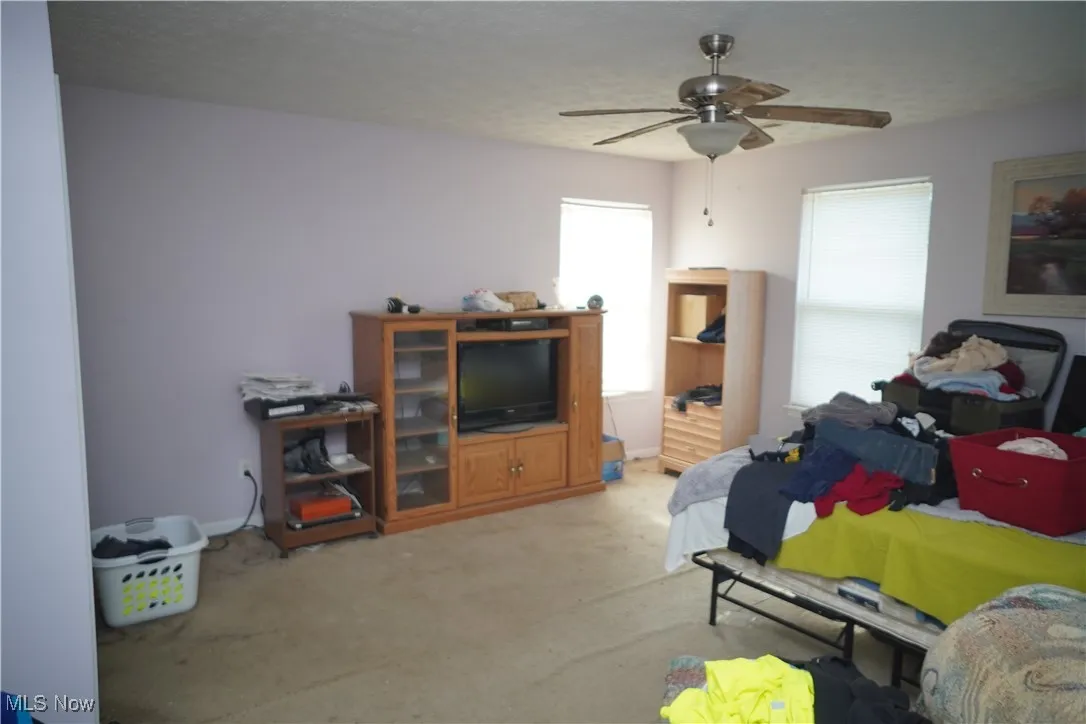 Bedroom with a textured ceiling, carpet flooring, and ceiling fan